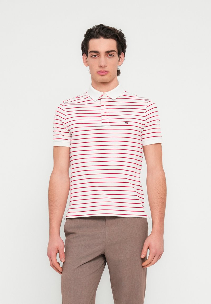 Πολο πουκάμισο με κόκκινες και λευκές ρίγες, με γιακά και κοντά μανίκια, στο στήθος διακοσμημένο με μικρό κεντημένο λογότυπο.