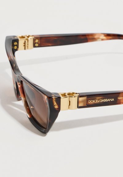 Τετράγωνα γυαλιά ηλίου με καβούρδισμα σε σχήμα χελωνότρατας, με χρυσούς μεταλλικούς μεντεσέδες και λογότυπο Dolce & Gabbana στο πλαϊνό μπράτσο.