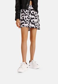 Gonna mini a righe bianco e nero con design svasato, abbinata a sneakers bianche con suola spessa e dettagli raffinati.