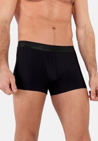 Boxer aderenti neri con una texture a coste e una vita liscia nera a contrasto. Il design offre una forma aderente e una copertura corta delle gambe.