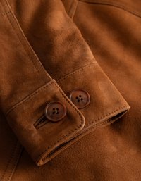 Bruin suède stof met een gladde textuur, voorzien van twee donkerbruine knopen en een gestikte manchet-detail.