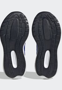 Sole in gomma nera con modelli di trazione testurizzati. Soletta bianca etichettata "CLOUDFOAM". Parte superiore in tessuto blu visibile ai bordi.