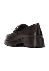Mocasín de cuero marrón con una suela de tracción resistente, puntera redonda y detalle de lazo decorativo. Textura suave con un acabado pulido.