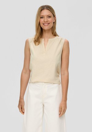 Light beige sleeveless top with a buttoned placket and gathered shoulders, paired with white wide-leg pants. Smooth texture, casual fit.