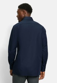 Marineblauwe langlopende shirt van gladde stof met een klassieke kraag, knoopmanchetten en een iets verlengde achterzoom.