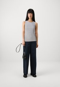 Gray sleeveless top with a rounded neckline, paired with navy wide-leg trousers and a small black handbag held by a thin strap.