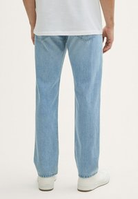 Lichtblauwe denim jeans met een recht model, vijf zakken, en subtiele stiksels, gecombineerd met witte sneakers.