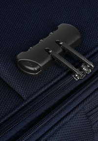 Valigia in tessuto blu navy in primo piano con una doppia cerniera nera e hardware metallico, che mette in mostra un materiale testurizzato e dettagli di cucitura.
