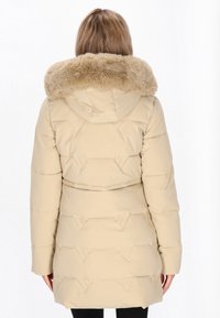 Beige pufferjakke med h�ætte og kunstpelskrave, der har en quiltet design og en indsnævret talje. Lange ærmer og lommer inkluderet.