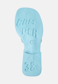 Light blue rubber shoe sole featuring embossed "CAMPER" and "38" details, along with a subtle design element resembling a splash.