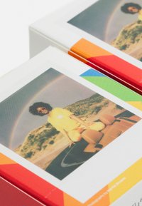 Colorful packaging features a vibrant photo of a person in a yellow shirt and pink sunglasses, with a rainbow in the background.