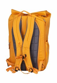 Mochila naranja con respaldo y correas de malla gris, que cuenta con hebillas ajustables y un cierre de tipo roll-top. Fabricada con un material duradero y con bolsillos.
