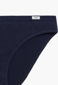 Ciemnoniebieskie bawełniane majtki o gładkiej strukturze, z białą metką z logo na pasku i prostym wzornictwie bez wzorów.