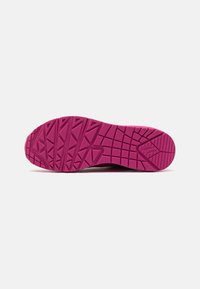 Semelle de chaussure de sport en caoutchouc rose vif, présentant un design texturé avec des rainures et des motifs angulaires pour une traction et une adhérence optimales.