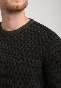 Suéter de punto verde oscuro con un patrón texturizado que presenta formas de diamante en relieve y un cuello redondo acanalado.