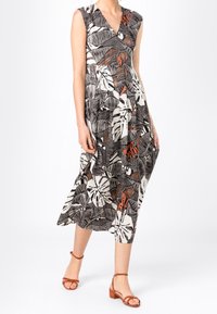 Robe sans manches avec un décolleté en V, imprimé de feuilles tropicales noir et blanc avec des accents orange ; silhouette fluide de mi-longueur, tissu léger.