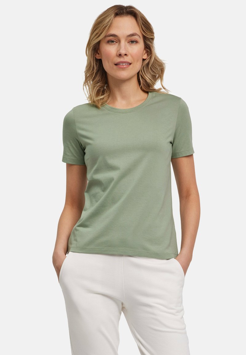 Lichtgroene, t-shirt met korte mouwen van zacht stof met een ronde halslijn. Heeft een ontspannen pasvorm en wordt gedragen met witte broeken.