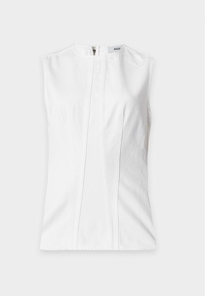 Blouse blanche sans manches avec un col rond, des coutures verticales devant et une fermeture éclair dans le dos.