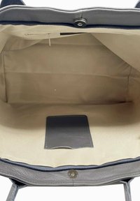 Szara skórzana torebka o gładkiej fakturze, z zamkiem błyskawicznym i beżowym wnętrzem. Zawiera małą kieszonkę oraz zapięcie na nap.