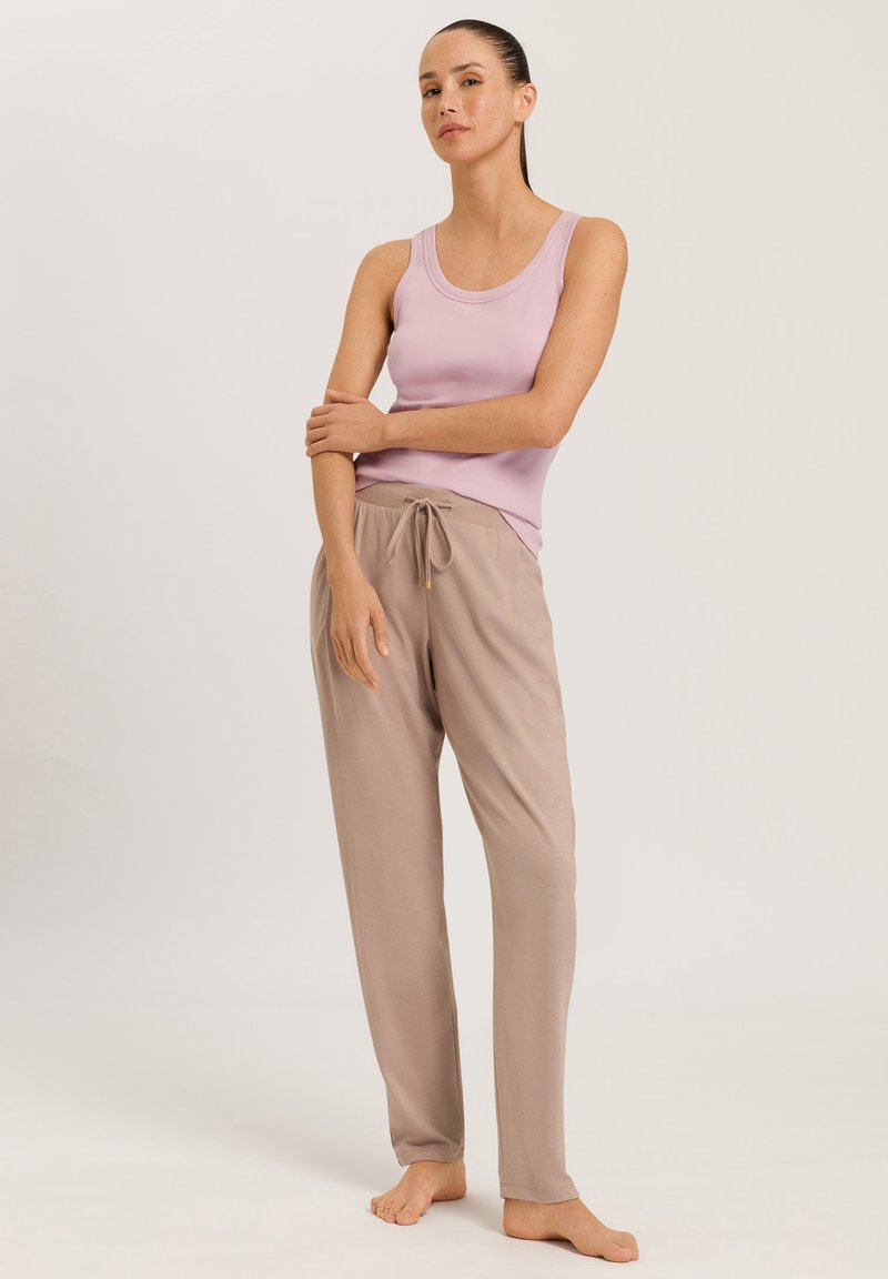 Entspannendes Outfit mit einem helllila Tanktop und beigen Jogginghosen, die aus glattem Material bestehen und lässig geschnitten sind.