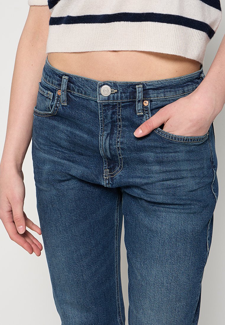 Blaue Denim-Jeans im klassischen Schnitt, mit einem Frontknopfverschluss und fünf Taschen. Der Stoff hat eine glatte Textur und leichte Verwaschungen.