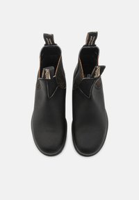 Bottines en cuir noir avec des panneaux élastiques sur les côtés, semelles en caoutchouc plates et languettes de tirage. Texture lisse avec des accents bruns contrastants.