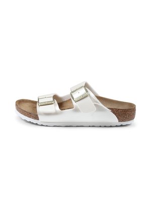 Sandales blanches à glissière avec deux bretelles réglables, semelle intérieure en liège et semelle en caoutchouc texturé. Présentent des boucles métalliques et un matériau supérieur lisse.