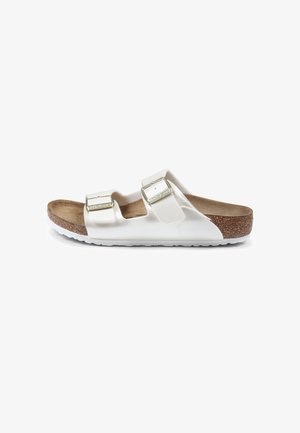 Witte schuifsandalen met twee verstelbare banden, een kurken voetbed en een gestructureerde rubberen zool. Voorzien van metalen gespen en een glad bovenmateriaal.