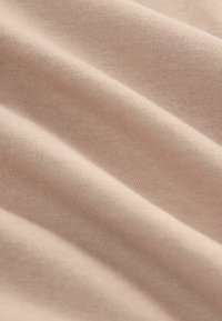 Světle růžová elastická tkanina s hladkou strukturou, která ukazuje jemný žebrovaný vzor a měkký splývavý efekt. Vhodná pro oblečení nebo doplňky.