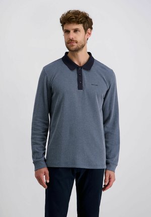 Polo a maniche lunghe di colore blu navy con un intricato motivo bianco, caratterizzato da un colletto scuro a tinta unita e una chiusura con patta a tre bottoni.