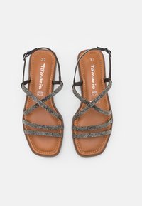 Sandali in pelle marrone con cinturini incrociati e dettagli metallici. Suola piatta con cuciture e punta quadrata, misura 37.