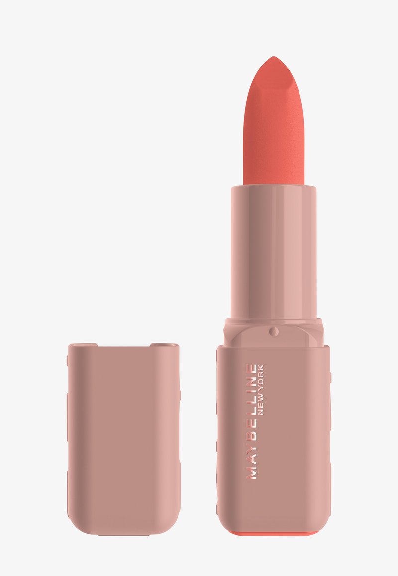 Maybelline-lippenstift in een beige cilindervormige huls, met een afgeronde koraalrode kogel. De dop is mat met subtiele merksdetails.