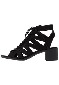 Czarne zamszowe sandały na obcasie z otwartym palcem, sznurowanym przodem i wyciętymi wzorami. Blokowy obcas i teksturowana podeszwa dla większej stabilności.