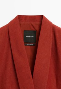 Blazer in lino rosso con design a revers. L'etichetta interna mostra "Massimo Dutti" e "Made in Portugal." Tessuto liscio.