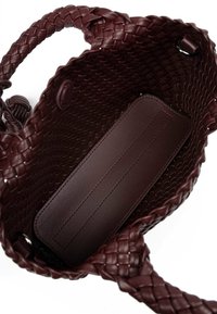Bordeaux handgeweven leren handtas met gevlochten handvatten, met een glad leren interieur en twee knoopsluitingen.