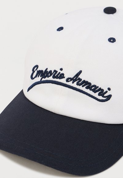 Άσπρο καπέλο μπέιζμπολ με μπλε σκούρο γείσο, με κεντημένο λογότυπο "Emporio Armani" σε καλλιγραφικό στυλ, δομημένη σχεδίαση και υφή υφάσματος.