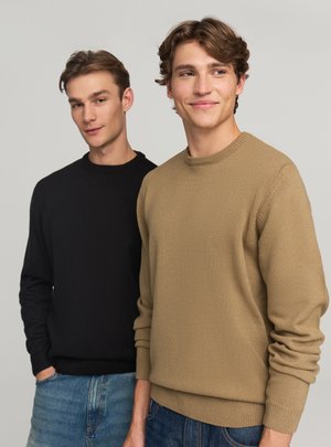 Due uomini che indossano maglioni leggeri in maglia testurizzata. Uno nero, l'altro beige. Entrambi con scollo rotondo e polsini a coste.