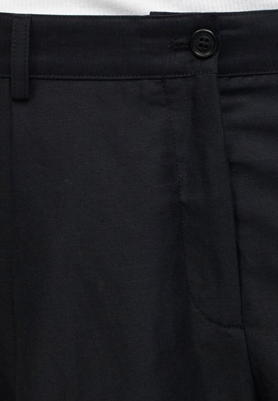 Μαύρη υφασμάτινη ζώνη παντελονιού με κλείσιμο με κουμπί και θηλιά για ζώνη, που δείχνει το πάνω μέρος και τη ραφή της τσέπης.