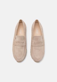 Mocassini in suede beige chiaro con punta rotonda, dettaglio della fascia frontale e suola in gomma. L'interno è dotato di un'imbottitura morbida per il comfort.