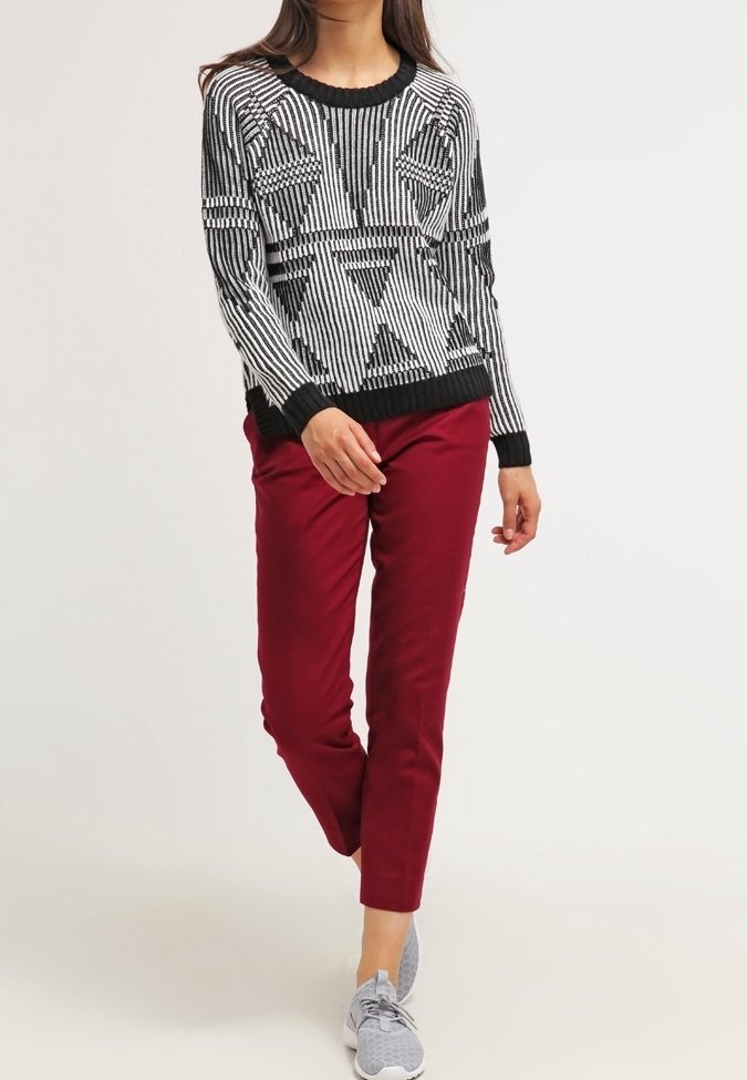 Svart- och vitrandig tröja med geometriska mönster, som matchas med vinröda byxor och grå sneakers. Avslappnad passform, ribbade kanter.