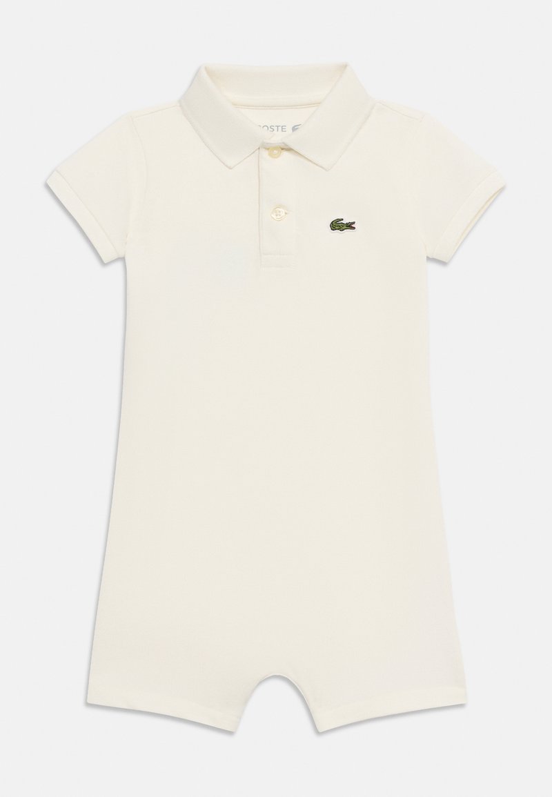 Grenouillère pour bébé à manches courtes de couleur crème avec col, deux boutons et un petit logo de crocodile vert sur le côté gauche de la poitrine.