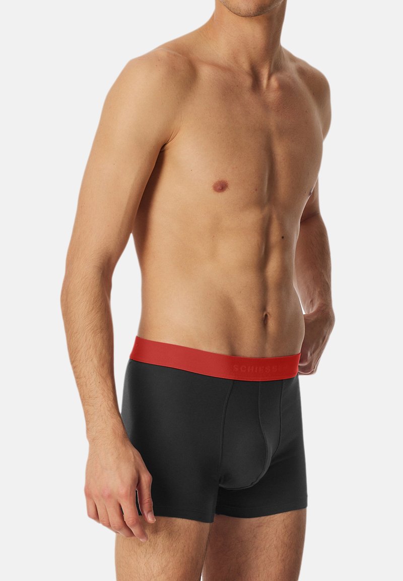 Sorte boxer briefs med en rød elastik. Materialet ser glat og strækbart ud, med et tætsiddende design og en frontpouch.