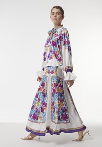 Long-sleeve floral blouse and matching skirt in white fabric. Features colorful floral patterns, ruffled accents, and bell cuffs with purple trim.