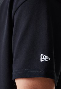 Black polo shirt featuring a textured fabric, short sleeves, and a small white logo on the left sleeve.