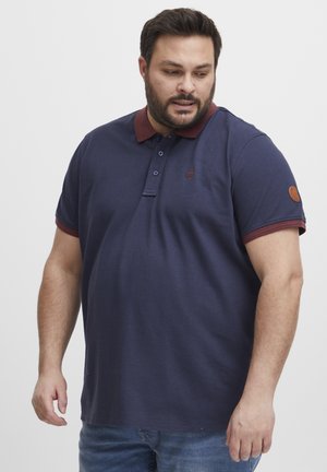 Navy polo shirt with a maroon collar and cuff accents, made from cotton, featuring a two-button placket and a small badge on the sleeve.