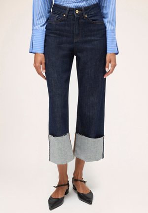 Donkerdenim cropped broeken met rafelige, lichtdenim manchetten en contrasterende stiksels. Voorzien van voorzakken en een knopenrits ontwerp.