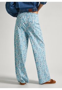 Světle modré kalhoty s potiskem a elastickým pasem, se květinovým vzorem na tyrkysovém pozadí. Volný, rovný střih s rozšířenými nohavicemi.