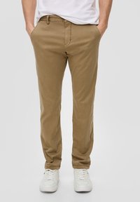 Beige Chinos mit Slim-Fit, aus Baumwollmischgewebe, mit Taschen und dezenten Nähten. Kombiniert mit weißen Sneakers.