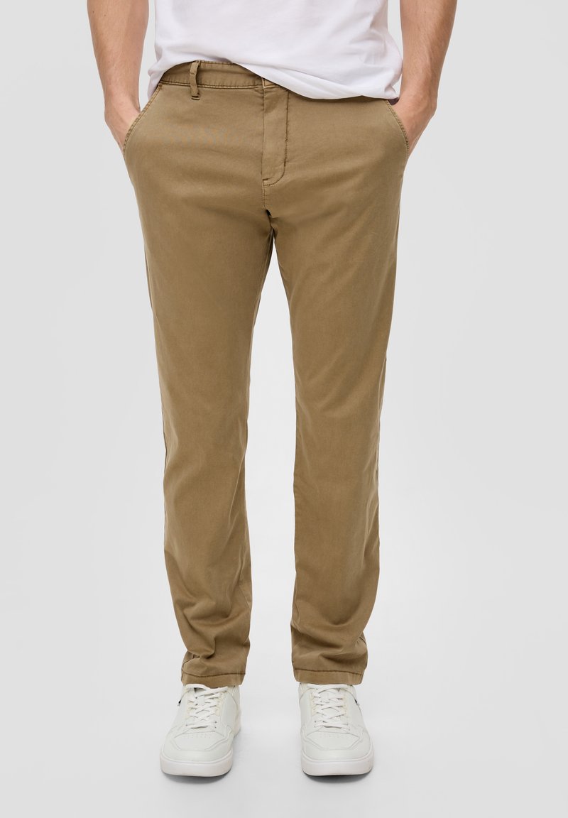 Beige Chinos mit Slim-Fit, aus Baumwollmischgewebe, mit Taschen und dezenten Nähten. Kombiniert mit weißen Sneakers.