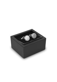 Srebrne spinki do mankietów z wygrawerowaną literą "D" w okrągłym designie, umieszczone w czarnej prostokątnej pudełku z miękkim czarnym wnętrzem.